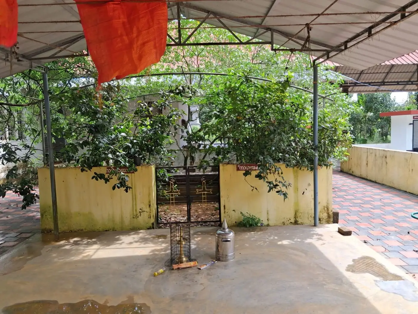 ക്ഷേത്രമുറ്റത്തെ തണലുള്ള ഒരു കോണും കാവിക്കൊടിയും